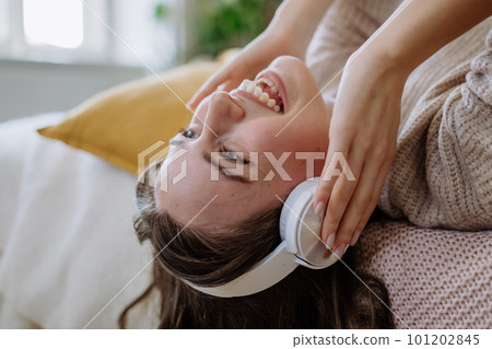 Young woman listening music trough headphones in her apartment. 101202845