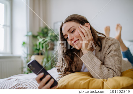 Young woman scrolling her smartphone in the apartment. Young woman scrolling her smartphone in the apartment. 101202849