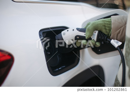 Close up of urecognizable person charging electric car. Close up of urecognizable person charging electric car. 101202861