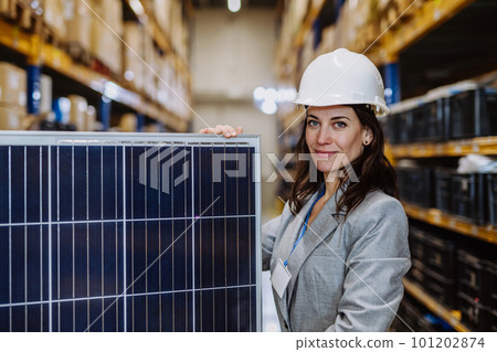 Portrait of manager holding a solar panel in a warehouse. 101202874