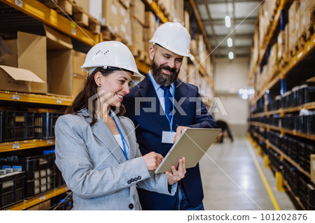 Managers in suit controlling goods in a waehouse. 101202876