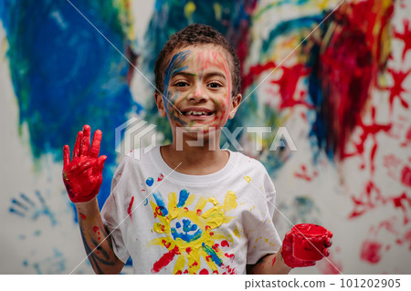 Portrait of happy boy with finger colours, painted t-shirt and background. 101202905