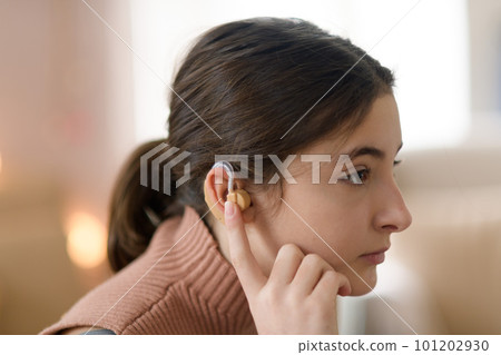 Portrait of teenage girl with hearing aid in her room. Portrait of teenage girl with hearing aid in her room. 101202930