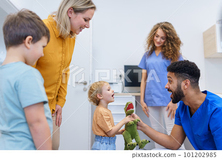 Young multiracial dentist playing with kids at his office. 101202985