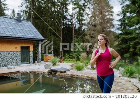 Young woman in sportive clothes jogging near mountain cottage. 101203120
