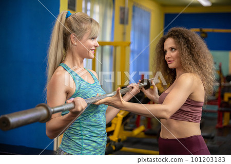 Fellow gym-goers exercising together help each other exercise Fellow gym-goers exercising together help each other exercise 101203183