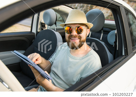 Bearded man using digital tablet inside car while travel and road trip vacation holidays - road map and navigation concept 101203227