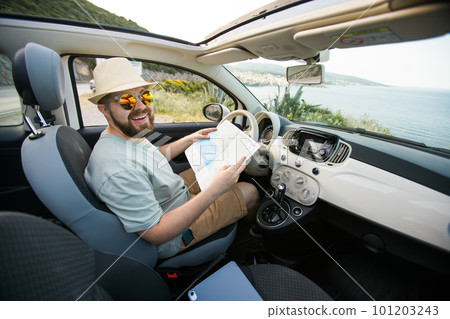 Hipster man looking on location navigation map in car, tourist traveler driving and hold in male hands europe cartography, view and plan tourist way road, trip in transportation cabriolet auto Hipster man looking on location navigation map in car, tourist traveler driving and hold in male hands europe cartography, view and plan tourist way road, trip in transportation cabriolet auto 101203243