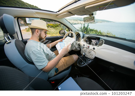 Hipster man looking on location navigation map in car, tourist traveler driving and hold in male hands europe cartography, view and plan tourist way road, trip in transportation cabriolet auto Hipster man looking on location navigation map in car, tourist traveler driving and hold in male hands europe cartography, view and plan tourist way road, trip in transportation cabriolet auto 101203247