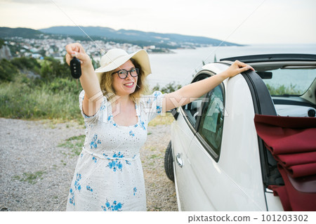 Travelling woman holding keys to new car and smiling at camera - ownership and purchase automobile concept Travelling woman holding keys to new car and smiling at camera - ownership and purchase automobile concept 101203302