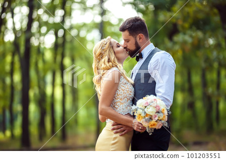 Stylish couple of happy newlyweds posing in the park on their wedding day. Perfect couple bride. 101203551