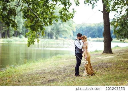 Stylish couple of happy newlyweds posing in the park on their wedding day. Perfect couple bride. 101203553