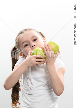 a little girl holds two green apples in her hands on a white background 101203682