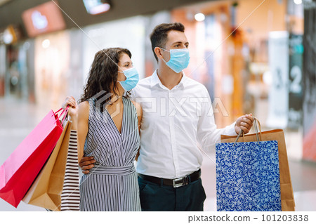 Young couple holding shopping bags, looking upon showcase and discuss shopping inside of mall. 101203838