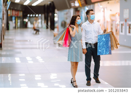 Young couple holding shopping bags, looking upon showcase and discuss shopping inside of mall. Young couple holding shopping bags, looking upon showcase and discuss shopping inside of mall. 101203843