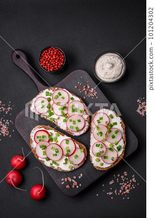 Delicious sandwich or bruschetta with cream cheese radish and green onions 101204302
