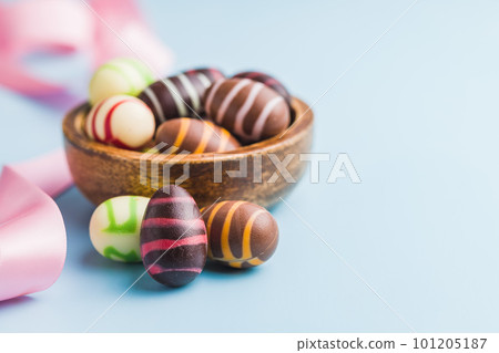 Chocolate easter eggs in bowl on blue background. Chocolate easter eggs in bowl on blue background. 101205187