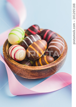 Chocolate easter eggs in bowl on blue background. Chocolate easter eggs in bowl on blue background. 101205188