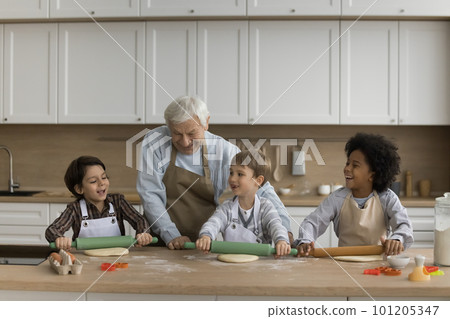 Happy grandpa and multiethnic grandsons in aprons preparing cookies 101205347