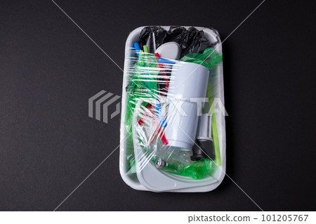 Set of plastic waste in a packed tray on a black isolated background. The problem of ecology and environmental pollution. 101205767