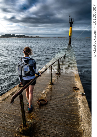 Young Woman At The End Of Bridge To Ferry Station To Ile De Batz At City Of Roscoff At The Finistere Atlantic Coast In Brittany, France 101206007