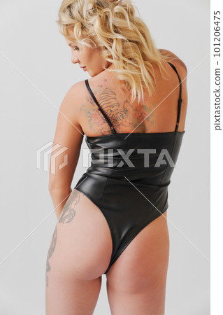 a sexy blonde with tattoos in a leather swimsuit. view from the back 101206475