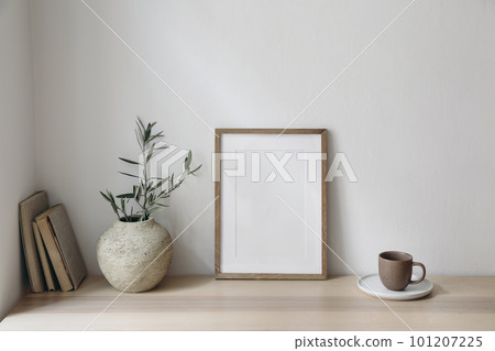Mediterranean breakfast still life. Cup of coffee, books. Empty wooden picture frame mockup on desk, table. Textured vase with olive branches. Elegant working space, home office. Scandinavian interior Mediterranean breakfast still life. Cup of coffee, books. Empty wooden picture frame mockup on desk, table. Textured vase with olive branches. Elegant working space, home office. Scandinavian interior 101207225