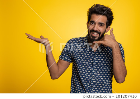 Bearded indian man looking at camera doing phone gesture like says hey you call me back conversation 101207410