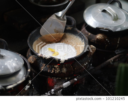 The making of a traditional Indonesian cake, originating from the Java region, named "surabi" is made from rice flour and placed in a small frying pan and topped with various toppings such as cheese.  101210245