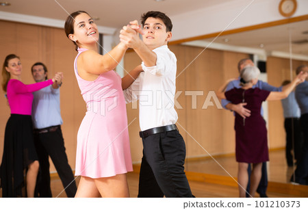 Young guy and girl enjoying slow foxtrot in dance studio Young guy and girl enjoying slow foxtrot in dance studio 101210373