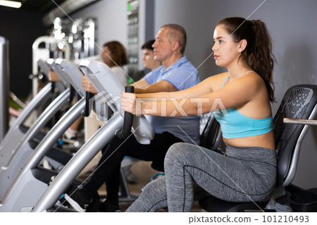 Young girl doing cardio training on stationary bike in gym 101210493