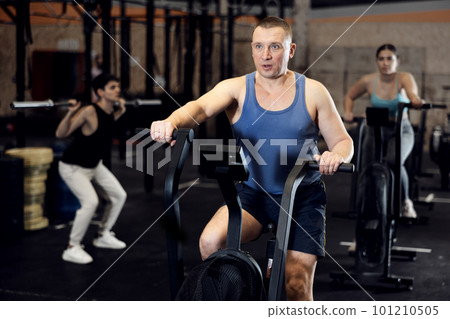 Man doing cardio training, cycling on stationary bike in gym Man doing cardio training, cycling on stationary bike in gym 101210505