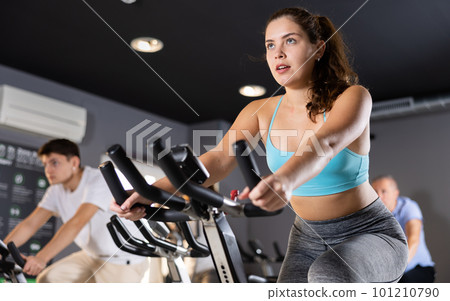 Young girl working out on stationary bicycle in gym 101210790