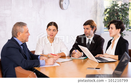 Business partners discussing projects at table in office 101210799