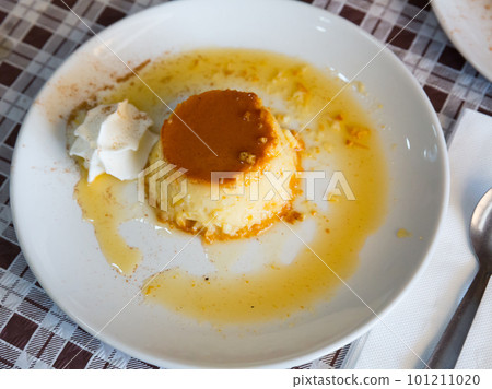 Tasty spanish dessert flan con nata served with caramel crust at plate 101211020