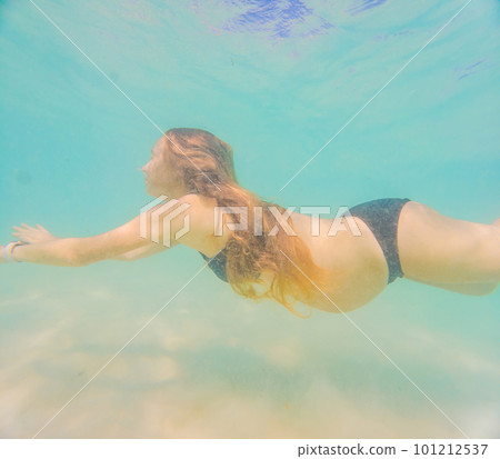 Pregnant woman underwater swimming in tropical sea. Healthy and active pregnancy. Young expecting mom on summer beach vacation before baby birth. Swim holiday and water fun. Travel during pregnancy Pregnant woman underwater swimming in tropical sea. Healthy and active pregnancy. Young expecting mom on summer beach vacation before baby birth. Swim holiday and water fun. Travel during pregnancy 101212537