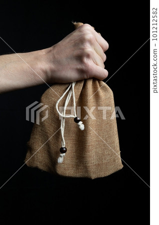 Man holding burlap bag in hands on black background Man holding burlap bag in hands on black background 101212582