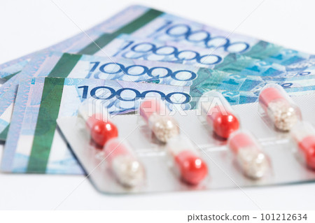 Blister with pills drug on top of stack of Tenge Kazakhstan money bills on white background Blister with pills drug on top of stack of Tenge Kazakhstan money bills on white background 101212634