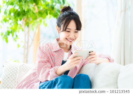 年輕女子在客廳看智慧型手機 101213545