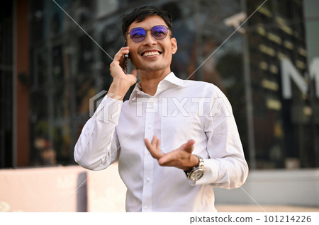 Professional Asian businessman is talking on the phone while walking in a city. 101214226