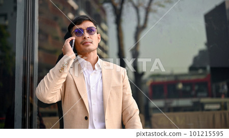 Professional Asian male CEO is on the phone while walking in a city. Urban lifestyle concept Professional Asian male CEO is on the phone while walking in a city. Urban lifestyle concept 101215595