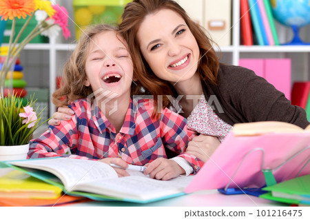 Portrait of a beautiful little cute girl with mother doing homework Portrait of a beautiful little cute girl with mother doing homework 101216475