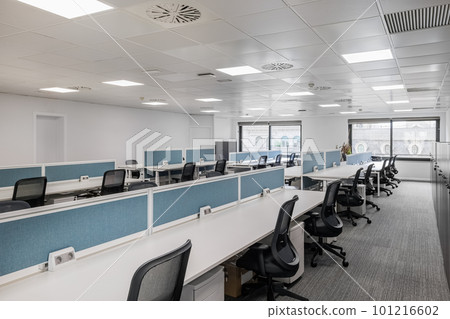 Empty office in gray tones with long tables and chairs for employees of managers with large windows with natural light. Concept of an office for corporate employees or coworking in a call center 101216602