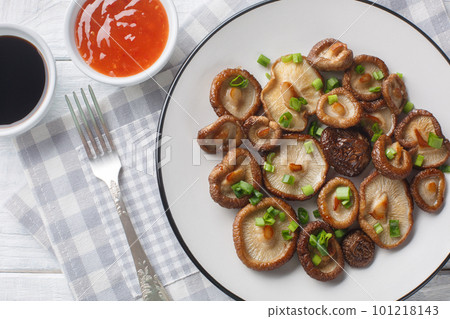 Appetizer fried shiitake mushrooms with green onions close-up on a white plate. Horizontal top view Appetizer fried shiitake mushrooms with green onions close-up on a white plate. Horizontal top view 101218143