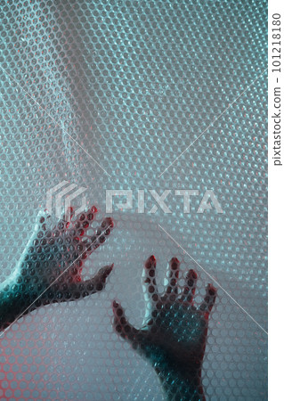 Nightmare horror. Emotional trap. Mental disorder. Defocused female hands clawing scratching transparent plastic bubble wrap textured wall free space background. 101218180