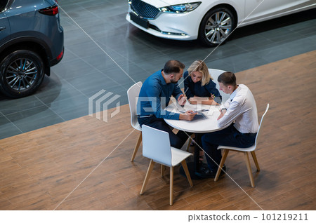 Happy caucasian couple signs a contract for the purchase of a car salon. 101219211