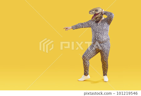 Funny overweight man having fun in rubber mask of dinosaur head isolated on orange background. 101219546