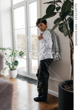 portrait of a pretty teenager standing near the window indoors and smiling at camera portrait of a pretty teenager standing near the window indoors and smiling at camera 101219770