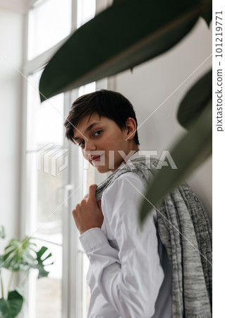 portrait of a pretty teenager standing near the window indoors and smiling at camera portrait of a pretty teenager standing near the window indoors and smiling at camera 101219771