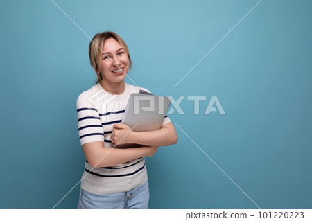 horizontal photo of a confident blonde woman freelancer in a striped sweater holding a laptop in her horizontal photo of a confident blonde woman freelancer in a striped sweater holding a laptop in her 101220223